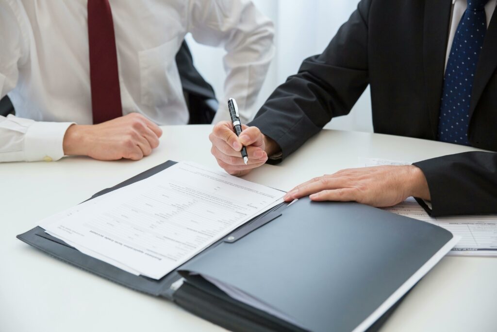 Two business people at a desk reviewing and signing paperwork as part of the Section 20 Landlord and Tenant Act 1985 consultation process.